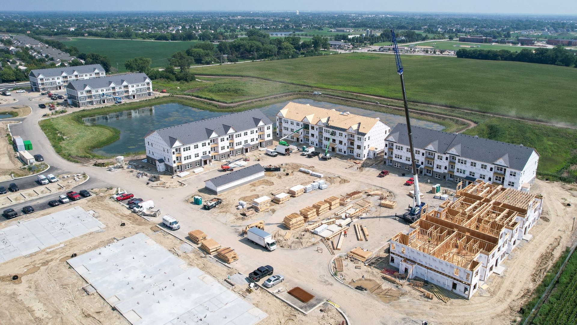 Large-scale commercial construction site aerial view showing multiple buildings under construction with crane and equipment